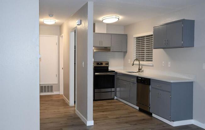 an empty kitchen with stainless steel appliances and a wooden floor