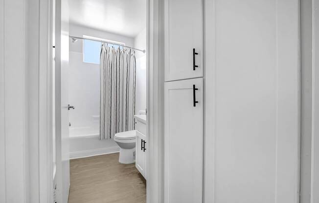 A white bathroom with a toilet, sink, and shower.