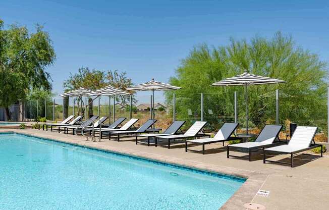 a swimming pool with chaise lounge chairs and umbrellas