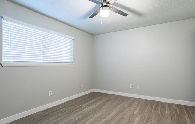 A room with a ceiling fan and a window with blinds.
