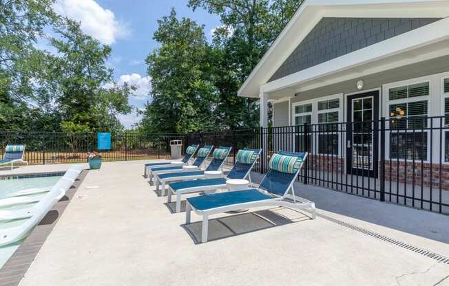 a pool with lounge chairs next to a house