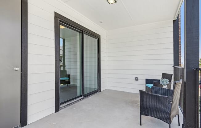 a covered patio with two chairs and a sliding glass door