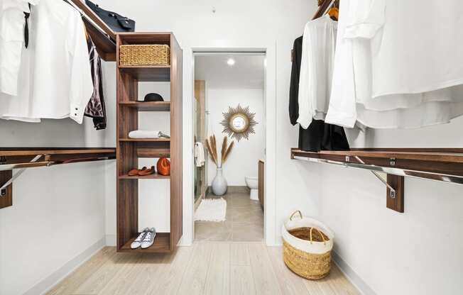 a walk in closet with wooden shelves and a door to the bathroom