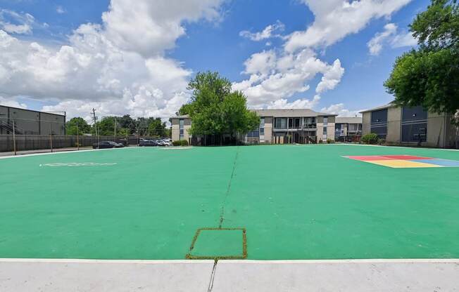 A basketball court with a green surface and a white line in the middle.