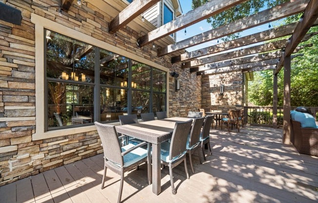 a patio with a wooden table and chairs and a pergola above it