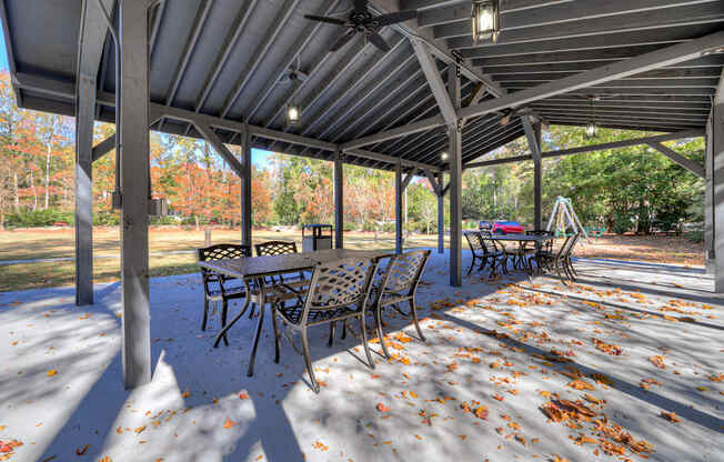 a covered patio with tables and chairs and leaves on the ground