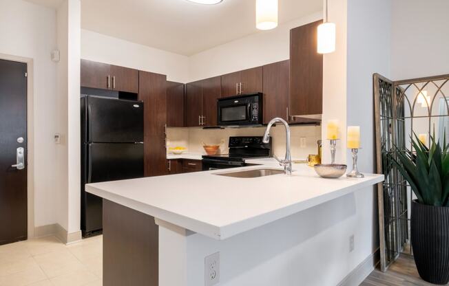 a kitchen with sleek, white counter tops and custom cabinetry at The Core apartments