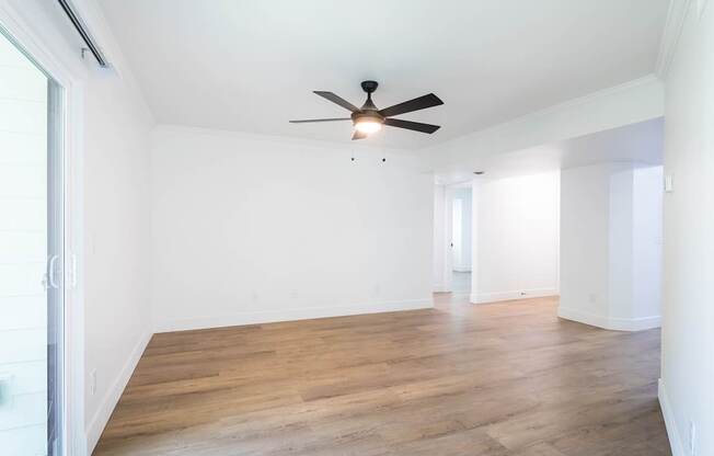 A room with a ceiling fan and wooden flooring.