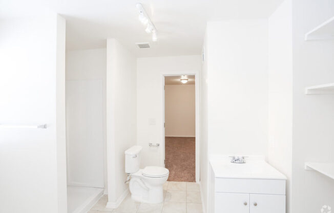 A white bathroom with a toilet, sink, and cabinet.