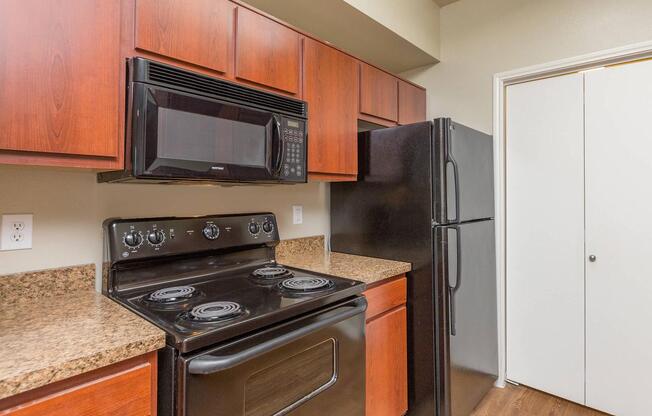 Black refrigerator, microwave and electric stove in galley-style kitchen at The Avenue