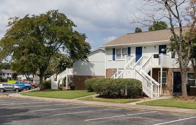 A white house with a blue door and a tree in front.