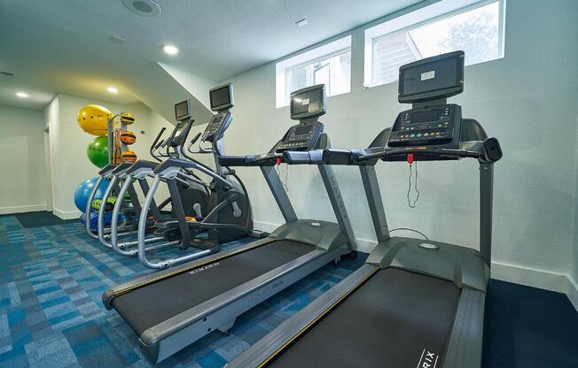 A treadmill and a stationary bike are in a gym.