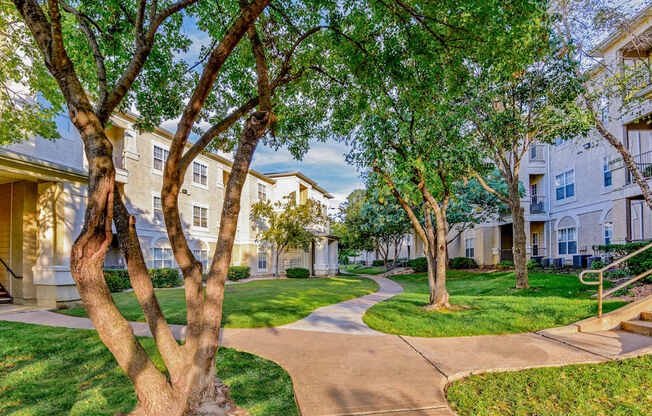 A tree-lined walkway leads to apartment buildings.