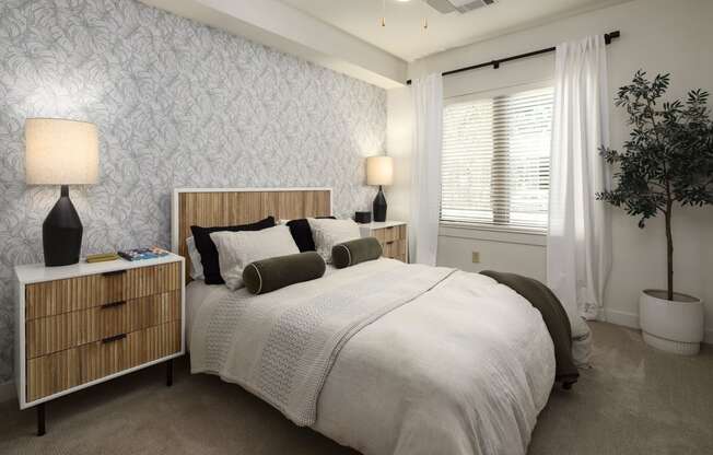 a bedroom with a bed and a window with white curtains