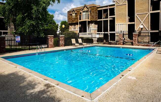 A swimming pool in front of a building with a fence around it.