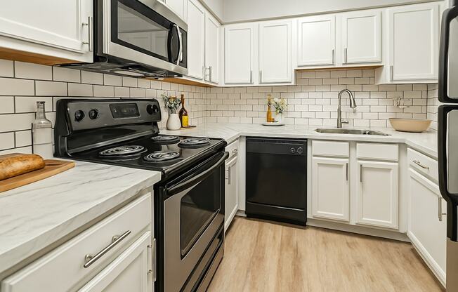 A kitchen with black and white appliances and wooden floors.