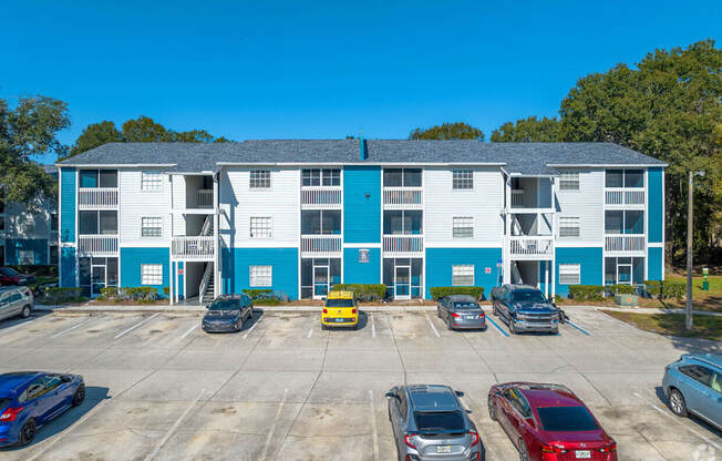 A parking lot with cars and a building with blue and white walls.