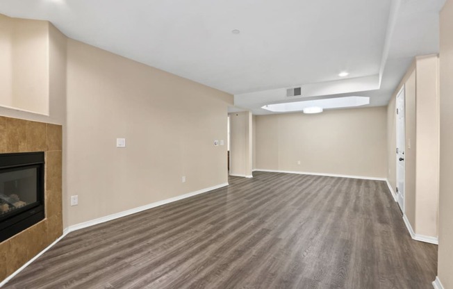 an empty living room with a fireplace and wood flooring