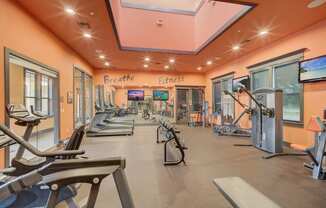 a gym with treadmills and other exercise equipment in a building with orange ceilings