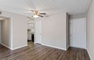A room with a ceiling fan and wooden flooring.