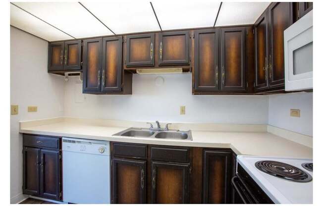 A kitchen with brown cabinets and white appliances.
