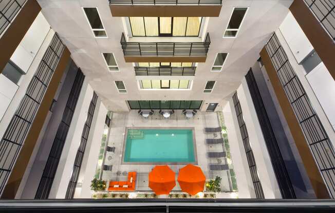 an overhead view of a hotel lobby with a pool and orange chairs