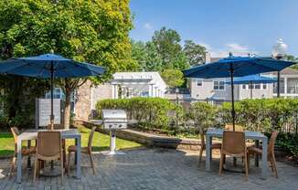 a patio with tables and umbrellas and a grill