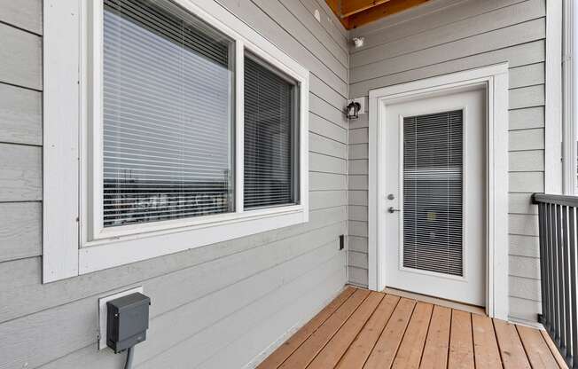 a front porch with a door and a window with venetian blinds