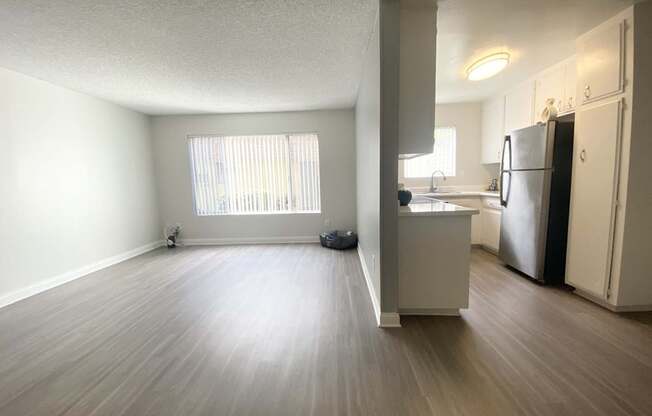 an empty living room and kitchen with a wood floor