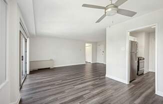 A room with a ceiling fan and wood flooring.