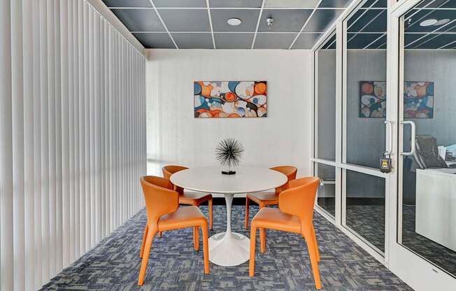 A conference room with a white table and orange chairs.