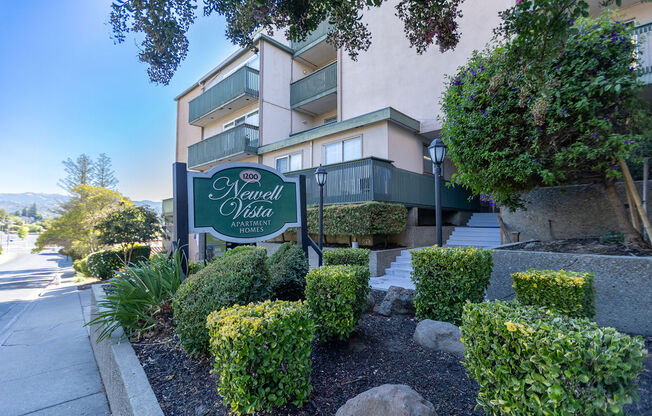 a building with a sign in front of a sidewalk and landscaping