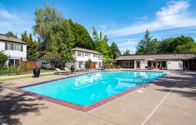 A swimming pool surrounded by a concrete patio and a fence.