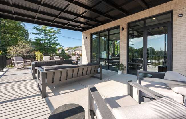 a patio with benches and chairs and glass doors