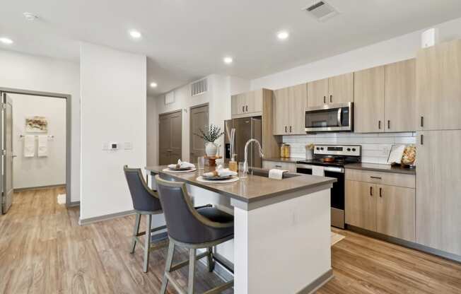 a kitchen with a large island with three stools at The Depot in The Depot Raymore, MO 64083