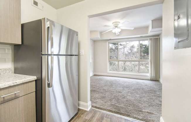 A stainless steel refrigerator in a kitchen with a window.