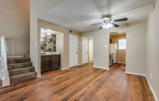 an empty living room and kitchen with a ceiling fan