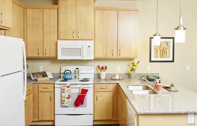  a kitchen with wooden cabinets and a granite countertop at The Cambric Senior Apartments, St. Paul, 55106