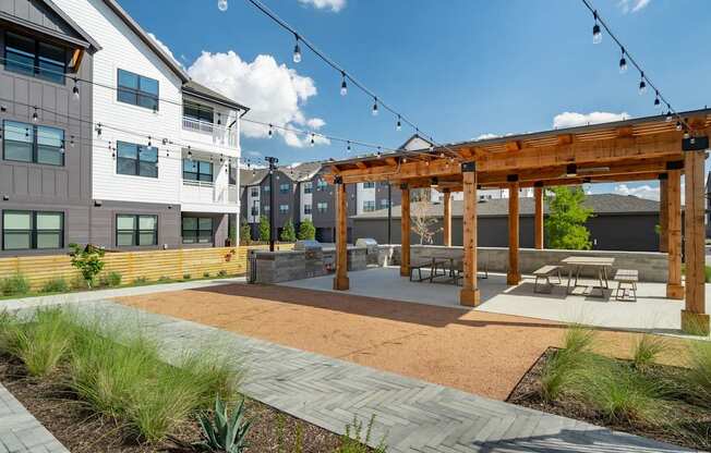a patio with a wooden pergola and string lights