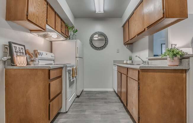 Galley Kitchen Featuring White Appliances & Oak Cabinetry