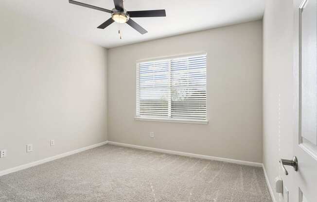 an empty room with a ceiling fan and a window