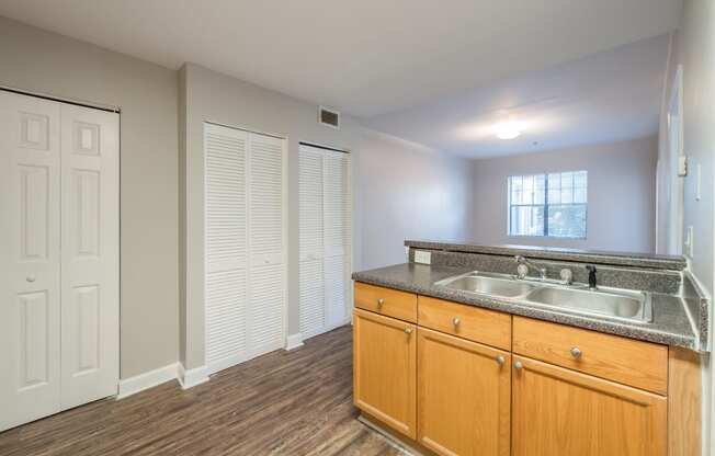 an empty kitchen with a sink and wooden cabinets at Crogman School Lofts, Atlanta, 30315