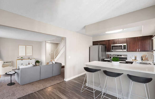 Model Kitchen with Dark Wood Cabinets, Wood-Style Flooring and View of Living Room at Horizon Apartments located in Santa Ana, CA.