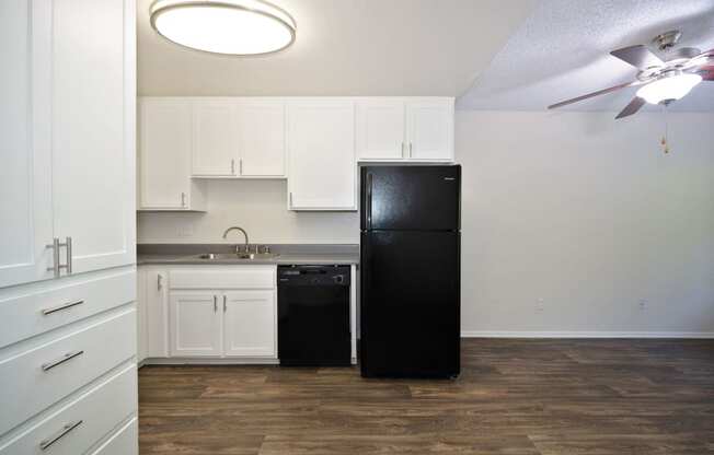 a studio apartment kitchen with white cabinets and a black refrigerator