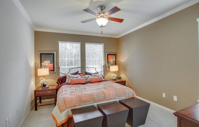 View of Bedroom with Ceiling Fan, Carpet, and Bed with Nightstands at Raveneaux Apartments