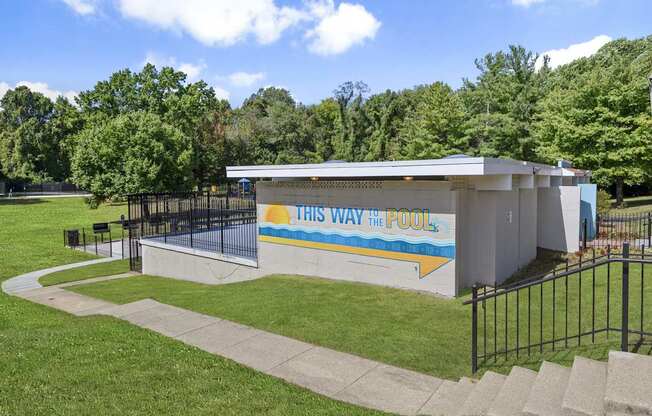 A pool building with the words "This Way to the Pool" on it.