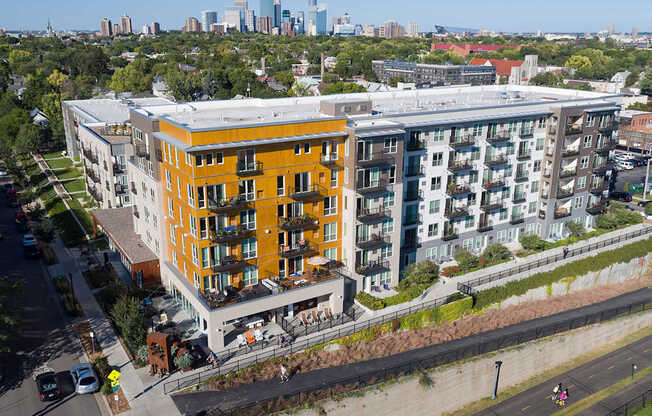 A modern apartment building with a mix of yellow and white balconies overlooks a city skyline.