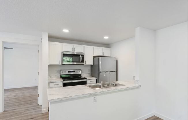 a kitchen with white walls and a wooden floor