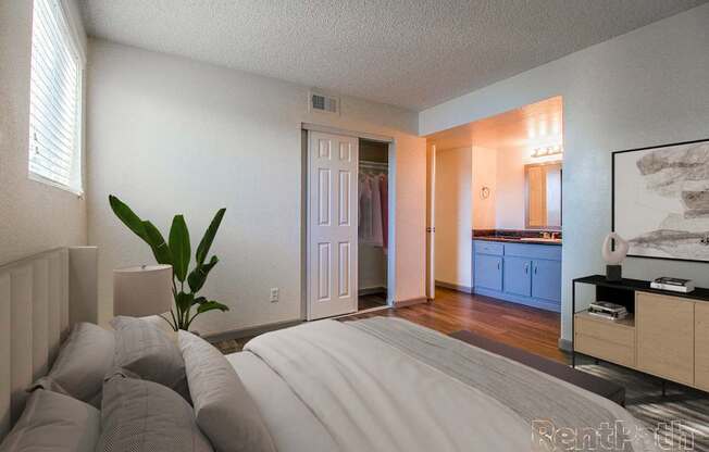 A bedroom with a large bed and a plant in a vase.