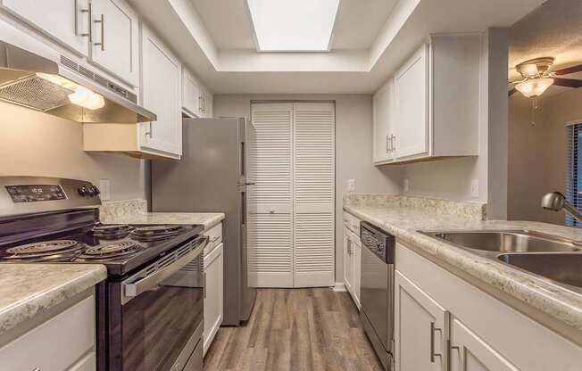 A kitchen with white cabinets and a stainless steel refrigerator.